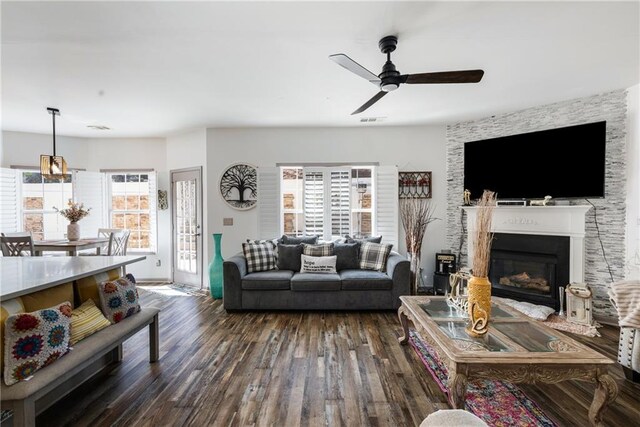 living area with visible vents, dark wood-type flooring, ceiling fan, and a fireplace