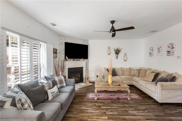 living room with visible vents, a fireplace, wood finished floors, and a ceiling fan