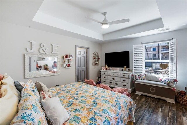 bedroom with a ceiling fan, a raised ceiling, wood finished floors, and visible vents