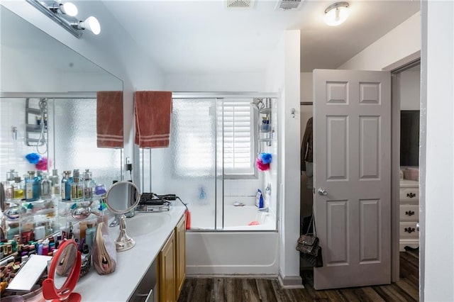full bathroom featuring combined bath / shower with glass door, visible vents, wood finished floors, and vanity
