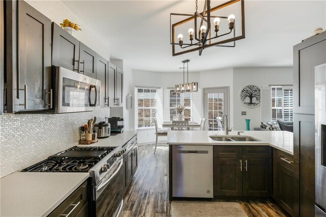 kitchen with a notable chandelier, appliances with stainless steel finishes, light countertops, and a sink