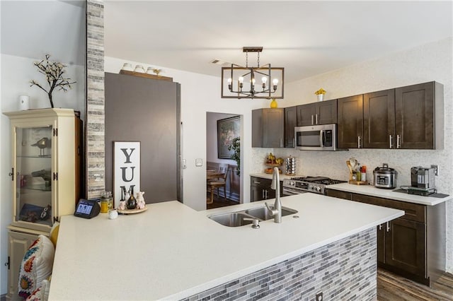 kitchen with dark brown cabinetry, stainless steel appliances, light countertops, and a sink