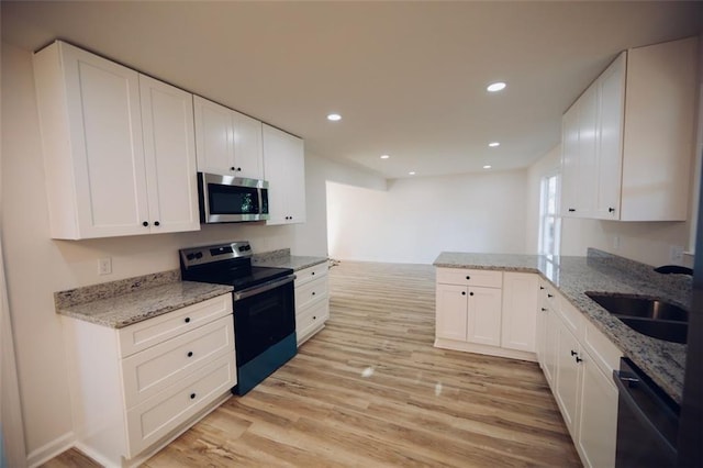 kitchen with kitchen peninsula, stainless steel appliances, sink, light hardwood / wood-style flooring, and white cabinets