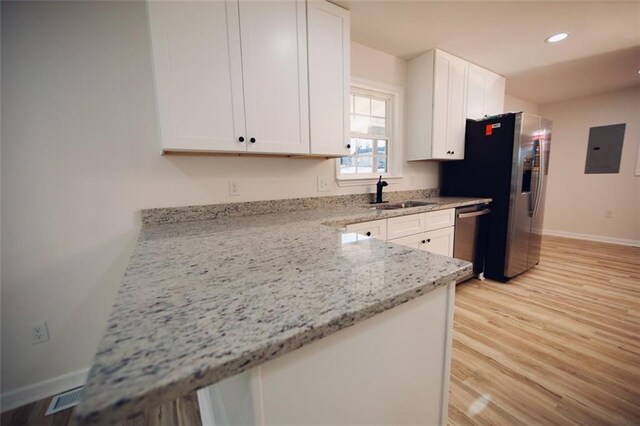 kitchen with light stone countertops, sink, stainless steel appliances, electric panel, and white cabinets