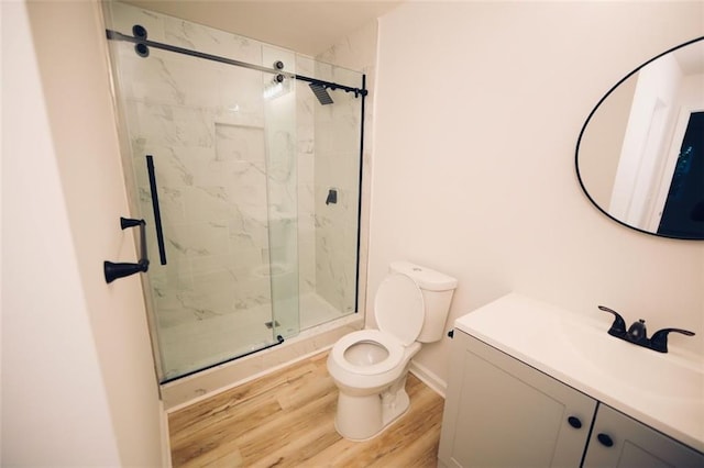 bathroom with hardwood / wood-style floors, vanity, toilet, and a shower with door