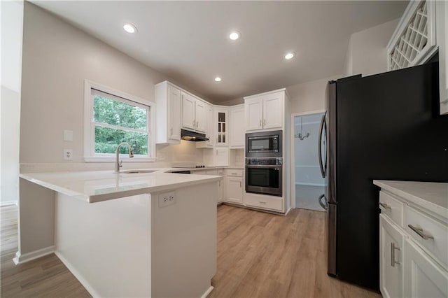 4495 Riders Ridge Trl, Snellville, GA 30039 - kitchen with appliances with stainless steel finishes, under cabinet range hood, a peninsula, a sink, and glass insert cabinets