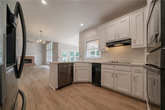 4495 Riders Ridge Trl, Snellville, GA 30039 - kitchen with black appliances, under cabinet range hood, a brick fireplace, white cabinetry, and recessed lighting