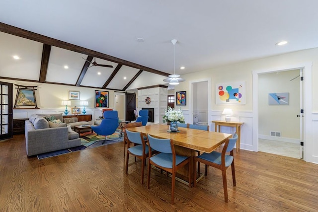 dining area with vaulted ceiling with beams, wood finished floors, visible vents, and a decorative wall