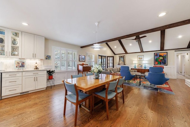 dining room featuring lofted ceiling with beams, ceiling fan, light wood-style flooring, a decorative wall, and visible vents