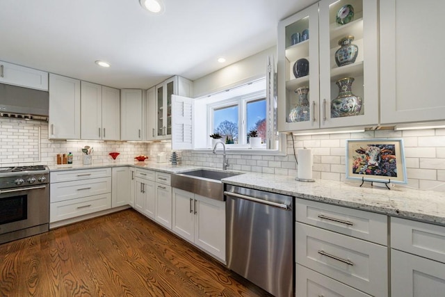 kitchen with dark wood-style flooring, stainless steel appliances, white cabinets, a sink, and extractor fan