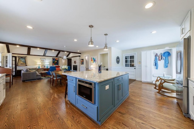 kitchen featuring vaulted ceiling with beams, stainless steel appliances, wood finished floors, and white cabinets