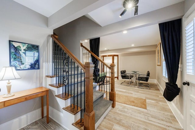 stairway featuring a wealth of natural light, recessed lighting, baseboards, and wood finished floors