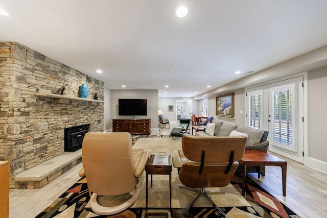 living room featuring french doors, recessed lighting, light wood-style flooring, a stone fireplace, and baseboards