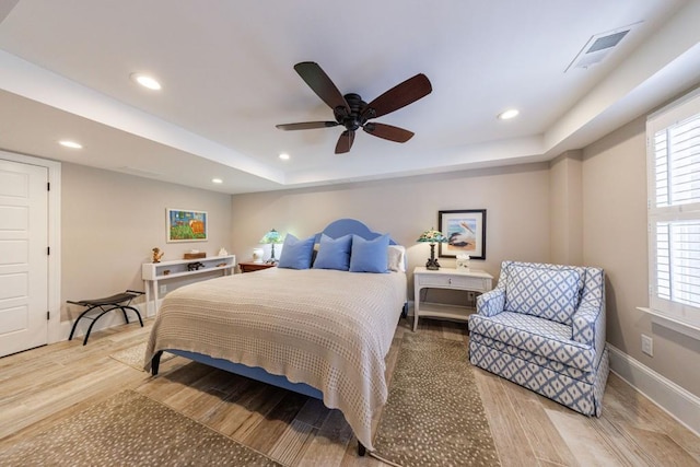 bedroom featuring recessed lighting, a raised ceiling, visible vents, wood finished floors, and baseboards