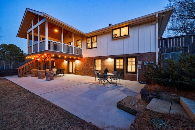 back of house featuring stairway, outdoor dining area, a patio, and brick siding