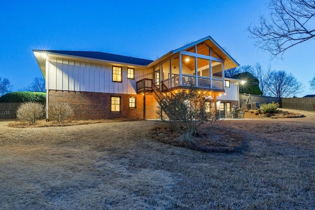 view of front of house featuring board and batten siding, brick siding, and fence