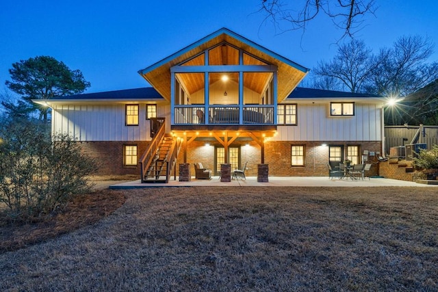 rear view of property featuring stairs, a patio, and brick siding