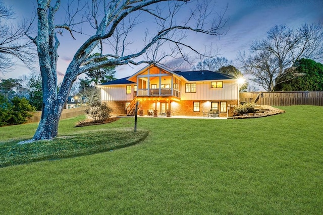 rear view of property with a fenced backyard, a lawn, stairway, and brick siding