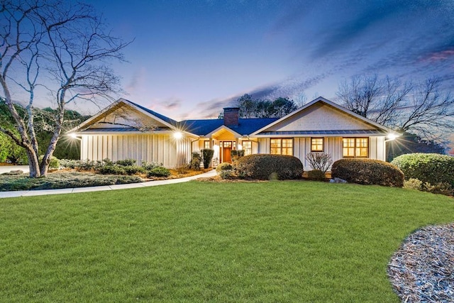 view of front of home featuring a yard, a chimney, and board and batten siding