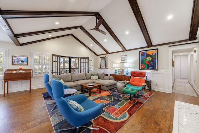 living area featuring a wainscoted wall, beam ceiling, a decorative wall, and wood finished floors