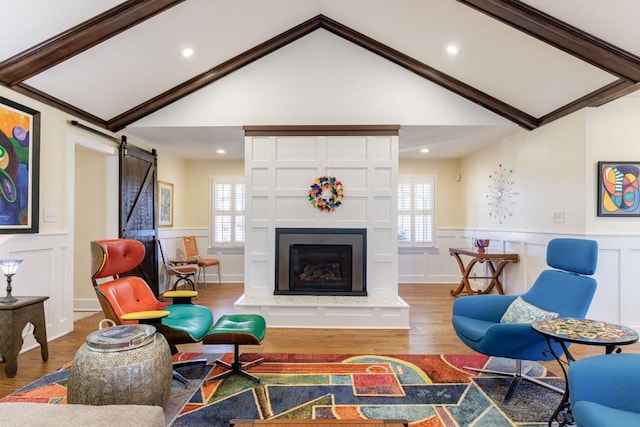 living area featuring vaulted ceiling, a barn door, plenty of natural light, and wood finished floors