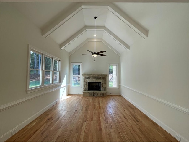 unfurnished living room with ceiling fan, beamed ceiling, a fireplace, high vaulted ceiling, and wood-type flooring