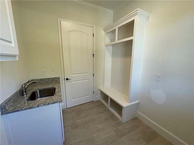 mudroom with ornamental molding, light tile floors, and sink