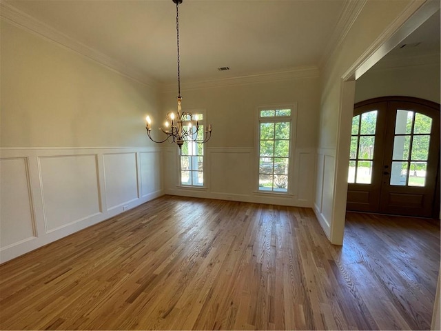 unfurnished dining area with ornamental molding, a notable chandelier, french doors, and dark hardwood / wood-style flooring