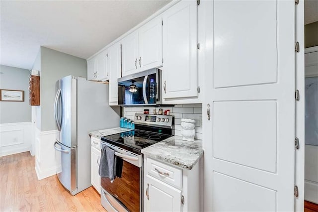 kitchen featuring light wood-type flooring, white cabinetry, backsplash, and stainless steel appliances