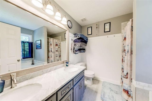 bathroom featuring double vanity, toilet, visible vents, and a sink