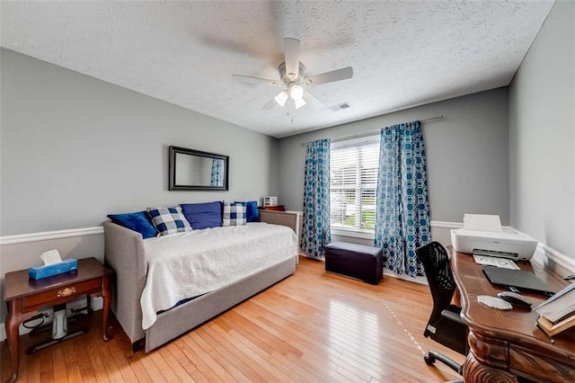 bedroom featuring visible vents, a ceiling fan, a textured ceiling, and hardwood / wood-style floors