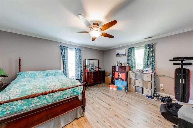 bedroom featuring crown molding, a ceiling fan, wood finished floors, and visible vents