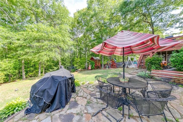 view of patio featuring fence, outdoor dining area, a playground, and stairs