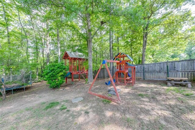 view of jungle gym featuring a trampoline and fence