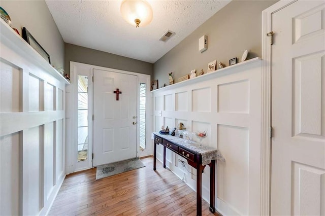 entryway with a textured ceiling, visible vents, and light wood-style flooring