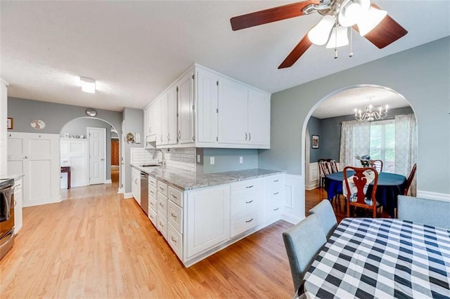 kitchen with white cabinets, light stone counters, light wood finished floors, arched walkways, and stainless steel dishwasher