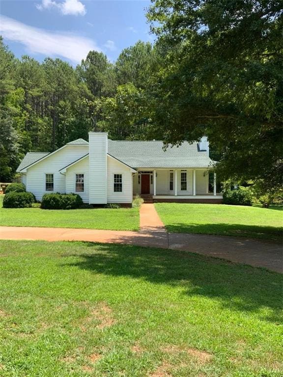 ranch-style home featuring covered porch and a front yard