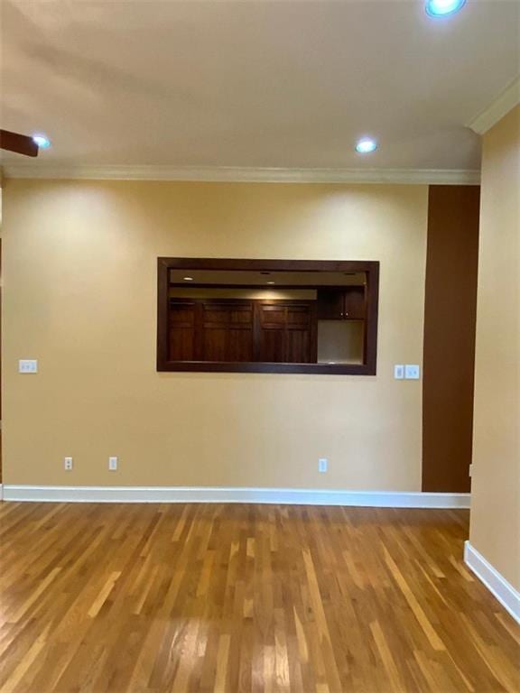 empty room featuring wood-type flooring and crown molding