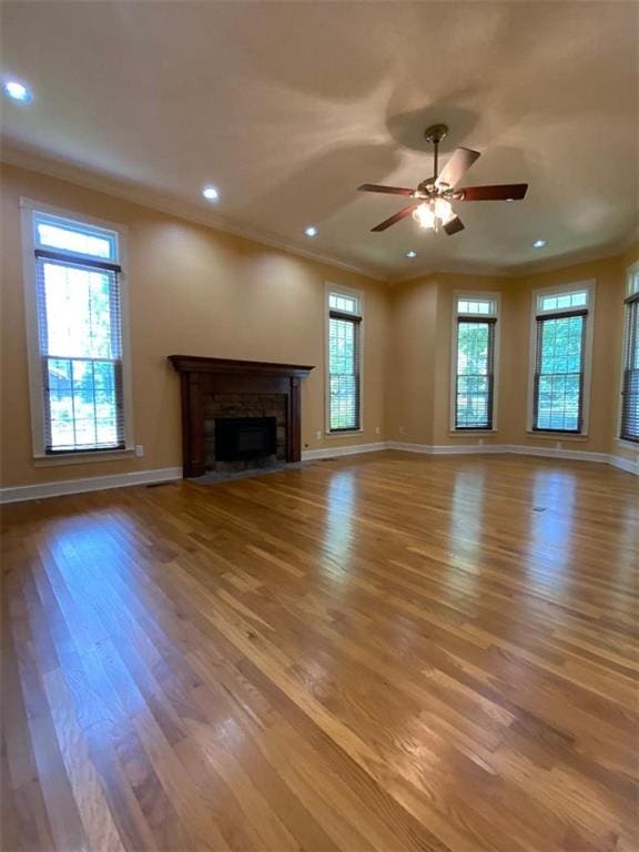 unfurnished living room with hardwood / wood-style floors, ceiling fan, ornamental molding, and a fireplace