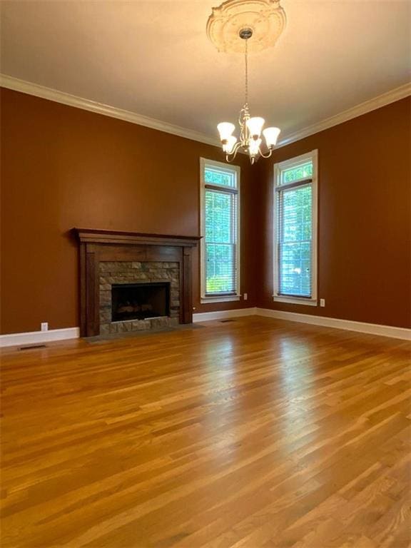 unfurnished living room with a fireplace, wood-type flooring, an inviting chandelier, and crown molding