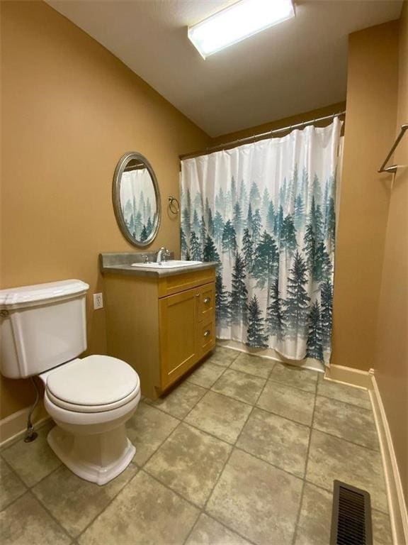 bathroom featuring vanity, toilet, and vaulted ceiling