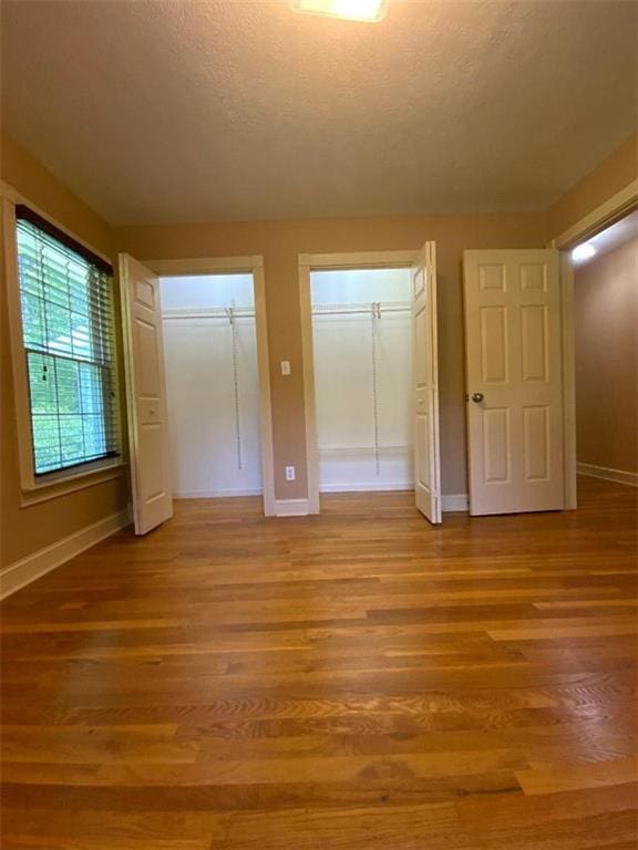 unfurnished bedroom featuring light hardwood / wood-style flooring and multiple closets