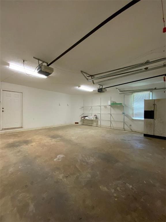 garage featuring white fridge with ice dispenser and a garage door opener