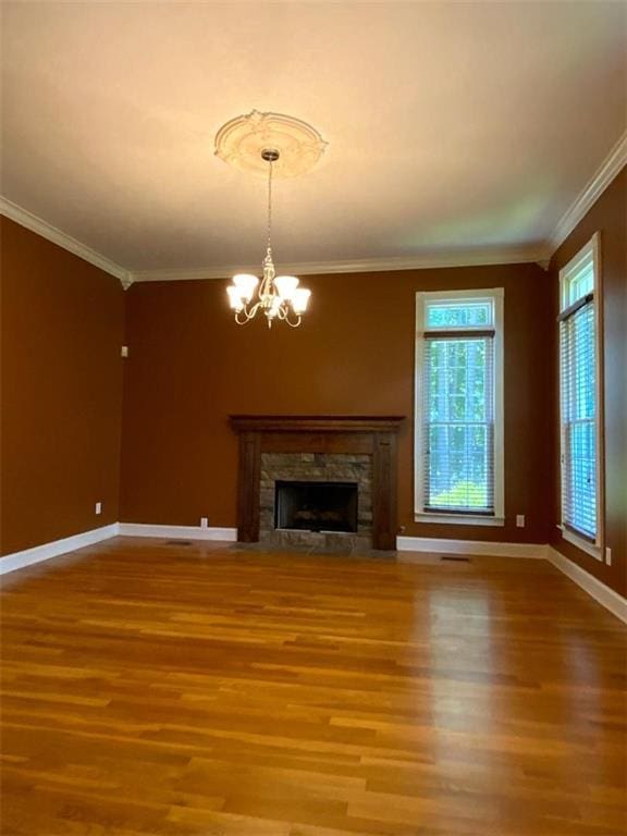 unfurnished living room with wood-type flooring, ornamental molding, a fireplace, and an inviting chandelier