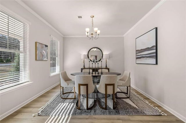 dining space with a notable chandelier, light wood-type flooring, and ornamental molding