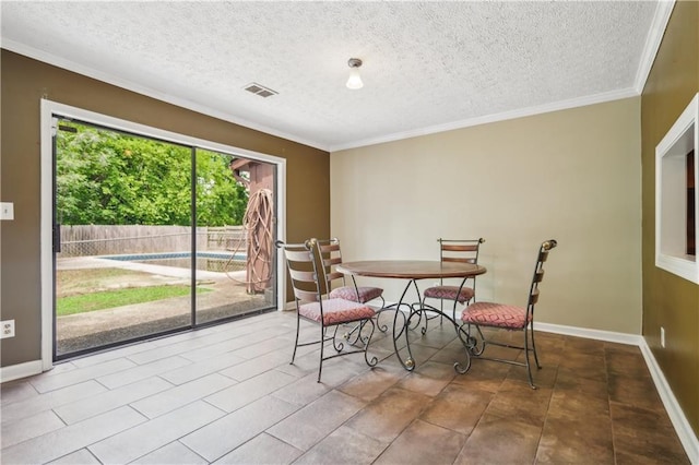 dining room featuring baseboards, ornamental molding, a textured ceiling, and visible vents