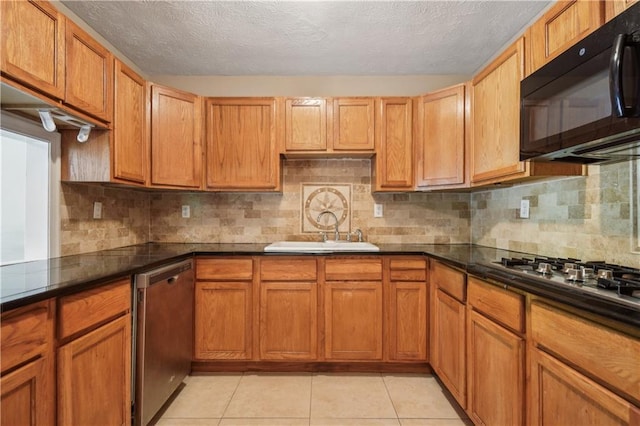 kitchen featuring a textured ceiling, appliances with stainless steel finishes, decorative backsplash, and a sink