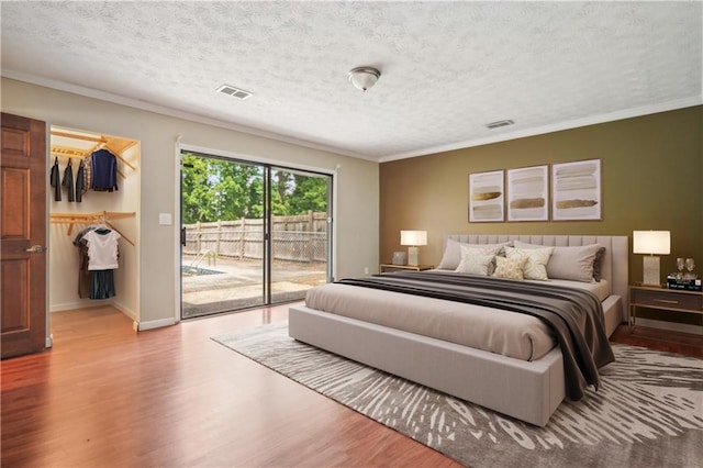 bedroom with visible vents, ornamental molding, wood finished floors, access to outside, and a spacious closet