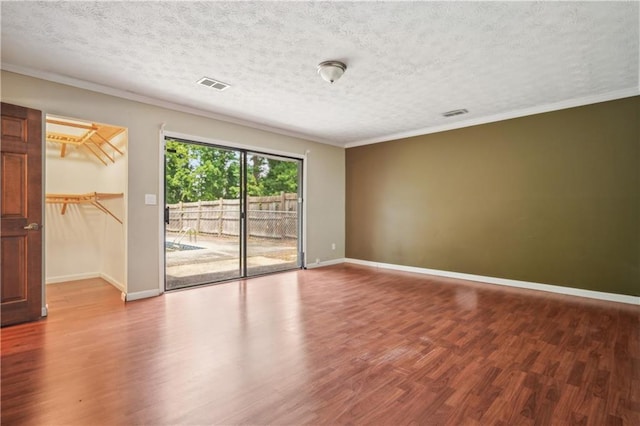 spare room with baseboards, visible vents, ornamental molding, and wood finished floors