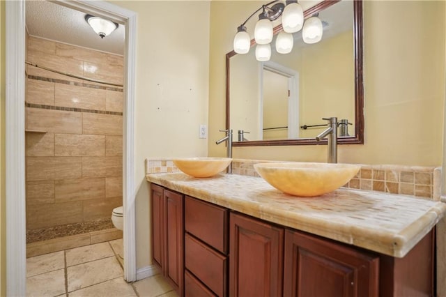 bathroom featuring a sink, tile patterned floors, toilet, and double vanity